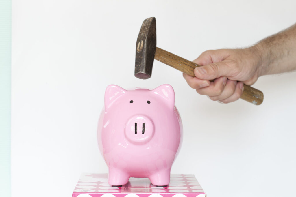 pink ceramic piggie bank being hit with a hammer