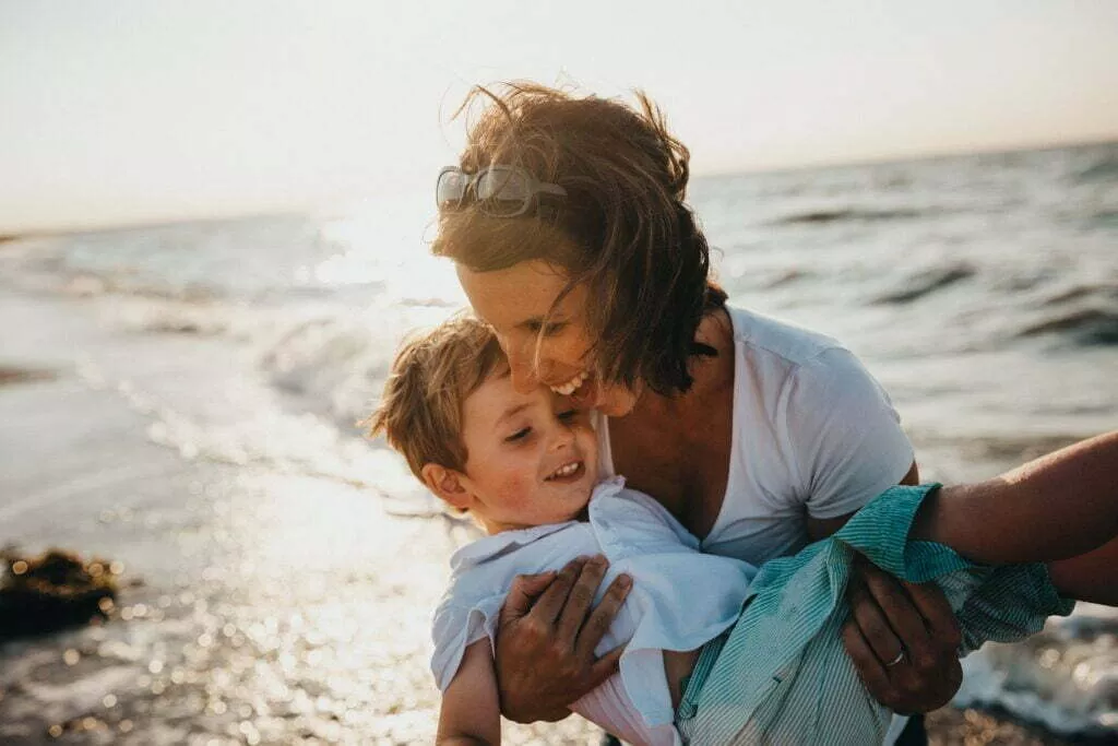 Woman Holding Child On Beach
