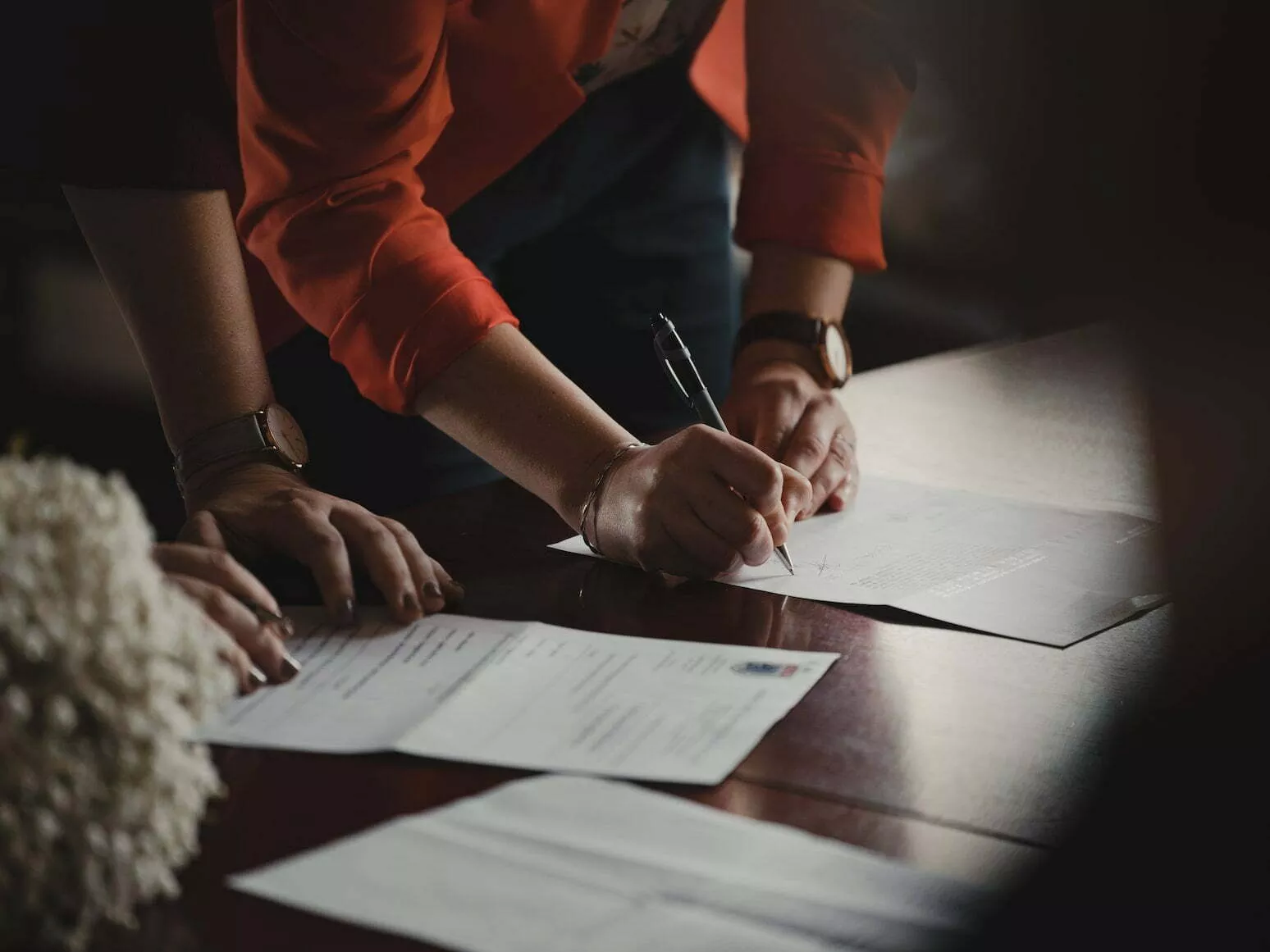 women-signing-reviewing-and-signing-documents-at-a-desk